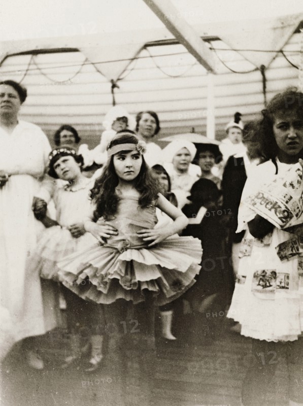 Fancy dress party aboard RMS Arundel Castle. A young girl, dressed in a ballet outfit with tutu, stands with her hands on her hips, looking rather displeased during a children's fancy dress party aboard RMS Arundel Castle, enroute from southern Africa to England. Location unknown, circa 1930.