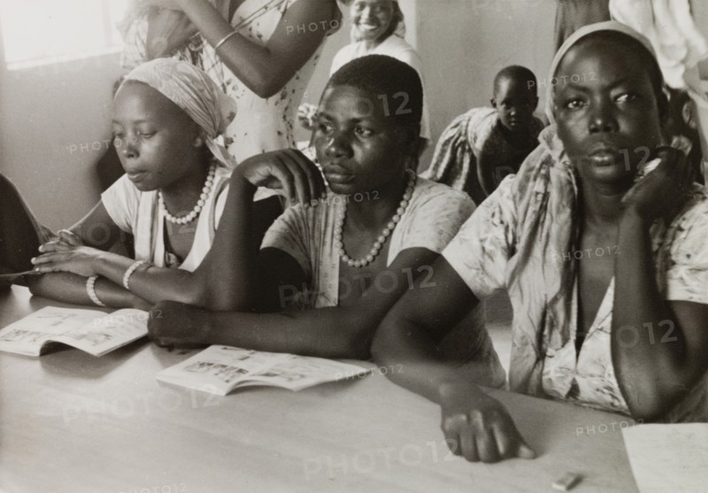 African women attend a missionary college. African women attend classes at a Methodist missionary college in Mombasa, sitting at a shared desk with their illustrated books open in front of them. Mombasa, Kenya, circa 1957. Mombasa, Coast, Kenya, Eastern Africa, Africa.