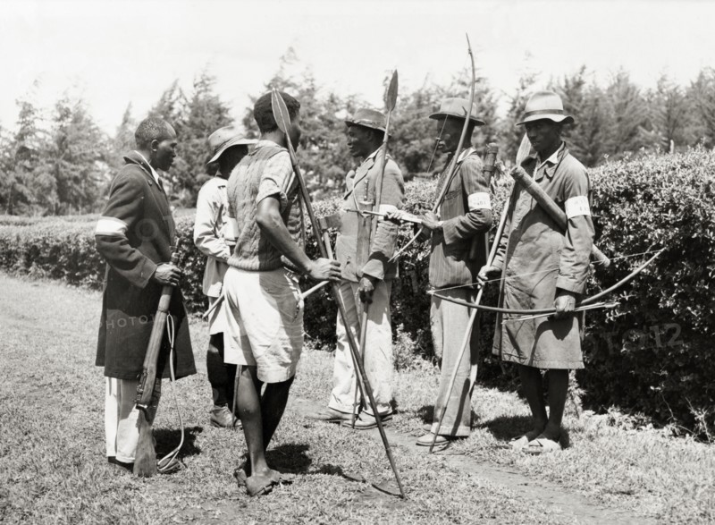Kikuyu Home Guards. An official photograph of six Kikuyu Home Guards, armed with spears and bows and arrows. One man carries a rifle. Nyeri, Kenya, 1952. Nyeri, Central (Kenya), Kenya, Eastern Africa, Africa.