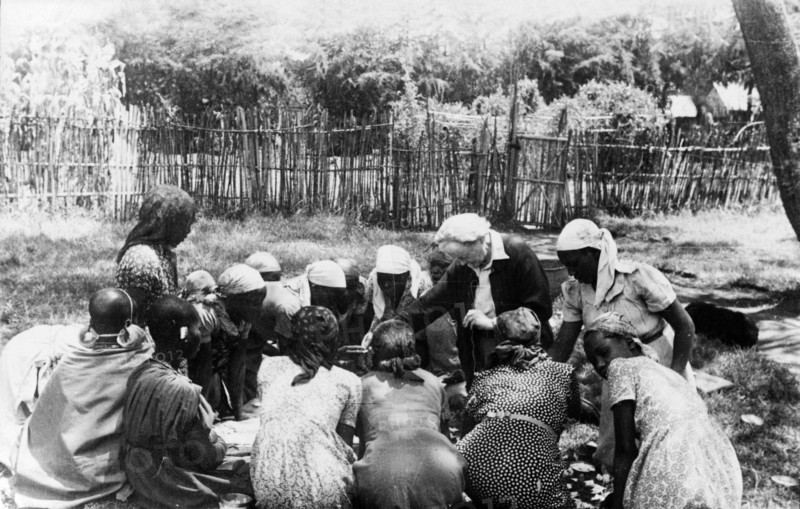 Nellie Grant teaches Kikuyu women. Nellie Grant, the wife of settler farmer Jos Grant and mother of Elspeth Huxley (nee Grant), teaches a domestic science class outdoors for the wives of Kikuyu farmers. Kenya, circa 1955. Kenya, Eastern Africa, Africa.