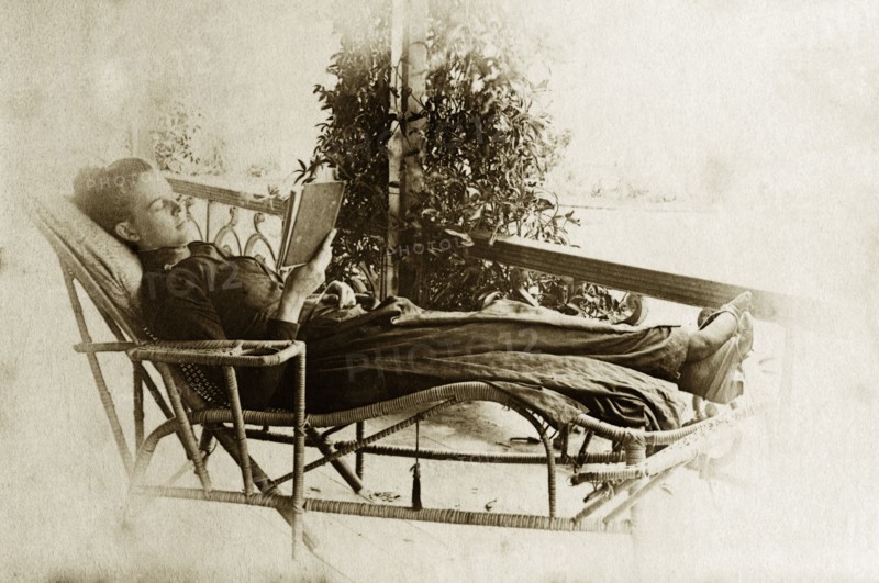 Relaxing on the veranda. Ellen May Pughe relaxes in a wicker chaise longue as she reads from a book on the veranda of a house. Near Brisbane, Australia, circa 1895., Queensland, Australia, Australia, Oceania.