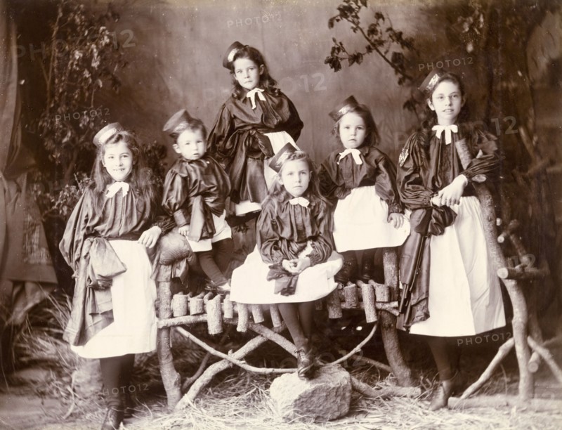 Portrait of girls in uniform, Murree. A family of girls pose for the camera wearing distinctive pinafore uniforms with hats pinned to the sides of their heads. Murree, Punjab, India (Punjab, Pakistan), circa 1895. Murree, Punjab, Pakistan, Southern Asia, Asia.