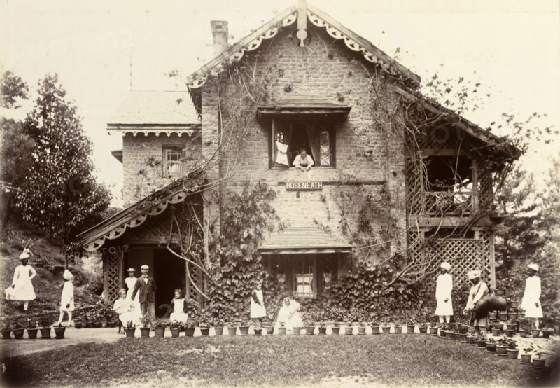 The Blount family at Roseneath. Pakistani servants dressed in white tend to the Blount family as they relax in the gardens of their house, 'Roseneath'. One individual waters the family's numerous potted plants from a large water bag supported on his shoulder. Murree, Punjab, India (Punjab, Pakistan), circa 1895. Murree, Punjab, Pakistan, Southern Asia, Asia.