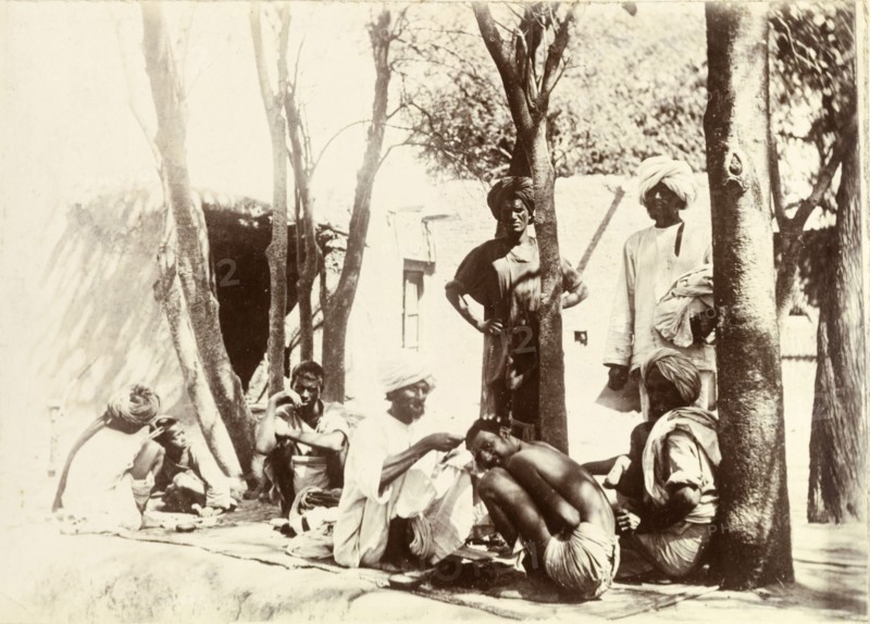 Indian street barbers. Turbaned Indian men sit on rugs in the street, providing a barber service for local men and boys. India, circa 1895. India, Southern Asia, Asia.