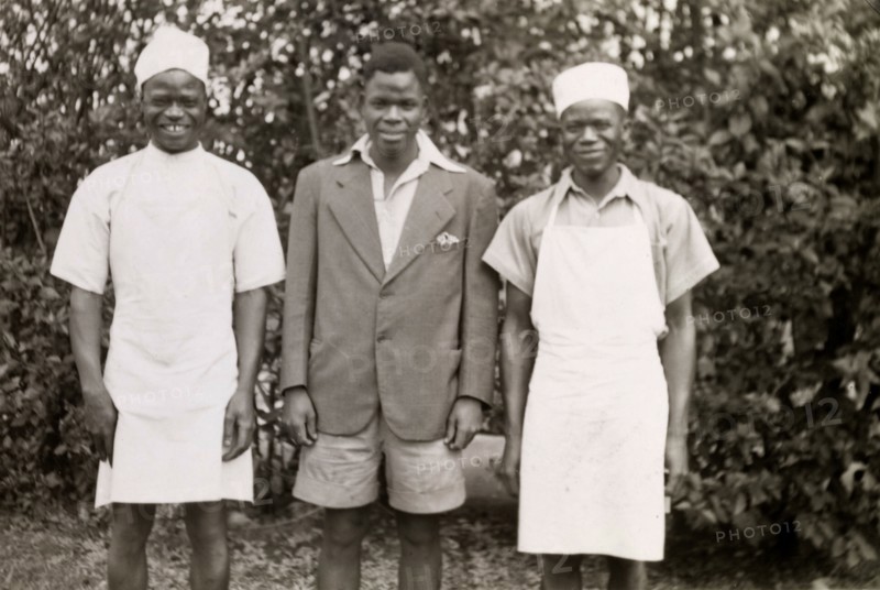 Domestic servants. Three domestic servants in workwear smile for the camera, their roles identified as (left to right): 'Cook, garden and house'. Salisbury, Southern Rhodesia (Harare, Zimbabwe), circa 1949. Harare, Harare City, Zimbabwe, Southern Africa, Africa.