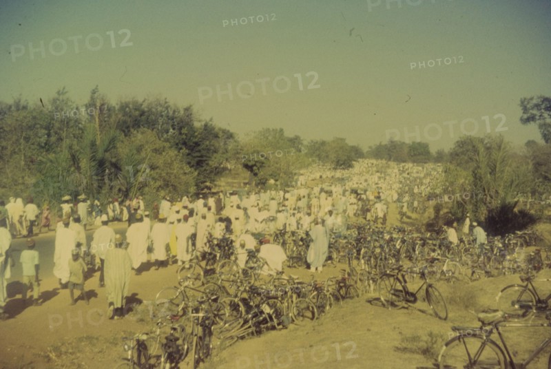 Procession for Ramadan. A procession held to celebrate the end of Ramadan heads into the distance past hundreds of bicycles parked on a roadside verge. Zaria, Nigeria, 1958. Zaria, Kaduna, Nigeria, Western Africa, Africa.