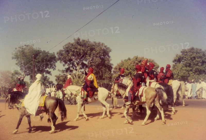 Procession for Ramadan. A group of Nigerian men dressed in ceremonial attire ride horseback in a procession celebrating the end of Ramadan. Zaria, Nigeria, 1958. Zaria, Kaduna, Nigeria, Western Africa, Africa.