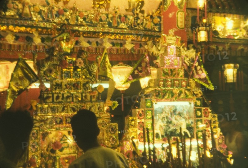 Festival stall, Hong Kong. Chinese lanterns illuminate a ornate festival stall decorated with gilded images, flags and incense. Hong Kong, People's Republic of China, September 1960. Hong Kong, Hong Kong, China, People's Republic of, Eastern Asia, Asia.