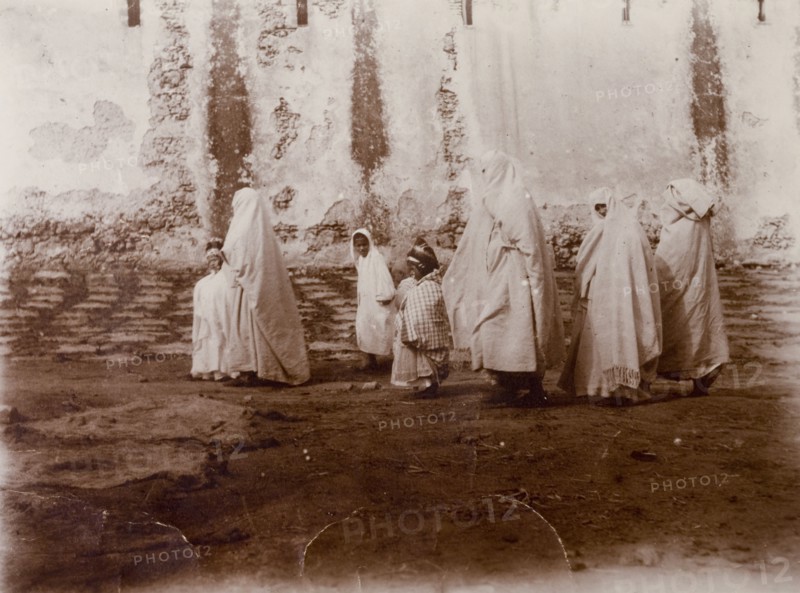 Moroccan women and children. Moroccan women shrouded in robes and headscarves marshal their children along the road. Morocco, 1898. Morocco, Northern Africa, Africa.