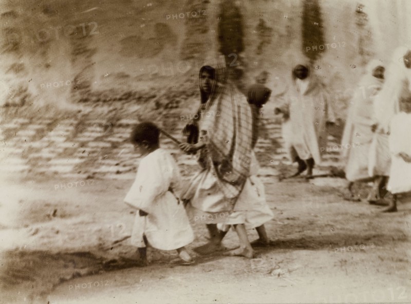 Morrocan woman and children. A young Moroccan woman, her head covered with a scarf, marshals her children through the city streets, Morocco, 1898. Morocco, Northern Africa, Africa.