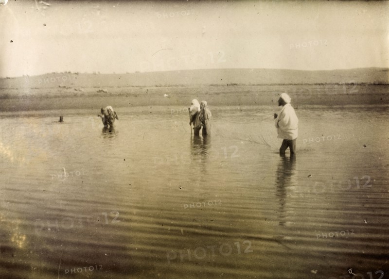 Fishing in south Morocco. A group of Moroccan men stand up to their knees in water, holding a fishing net stretched out between them in the middle of a shallow lake. Southern Morocco, 1898. Morocco, Northern Africa, Africa.