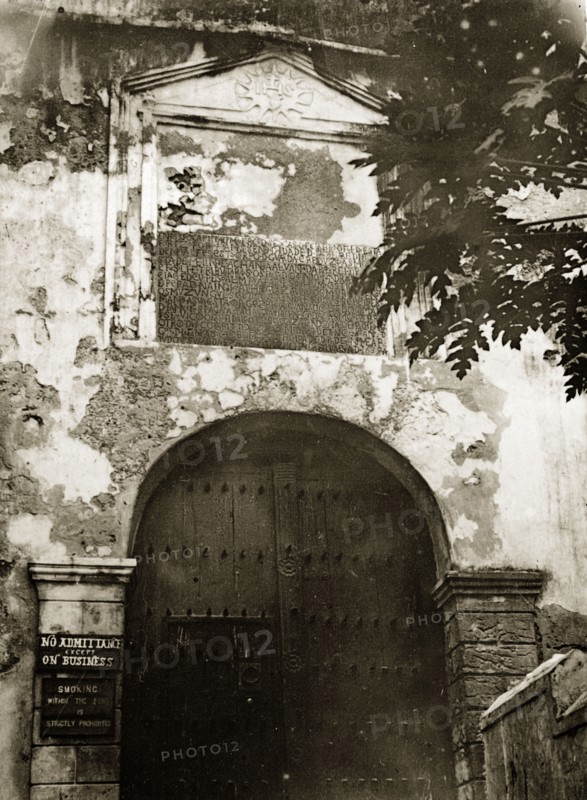 Entrance to the fort. A closed wooden doorway forms the entrance to a fortifed complex identified only as 'the fort'. A sign to the left of the door reads: 'NO ADMITTANCE EXCEPT ON BUSINESS'. Probably Kenya, 1906., Eastern Africa, Africa.