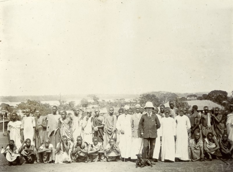 Tsetse fly researchers. A European official poses with Africans in a variety of costumes. A caption says they are 'in search of tsetse fly', suggesting that they were part of the colonial administration's attempt in the early twentieth century to map the distribution of tsetse fly in British East Africa. British East Africa (Kenya), 1906. Kenya, Eastern Africa, Africa.