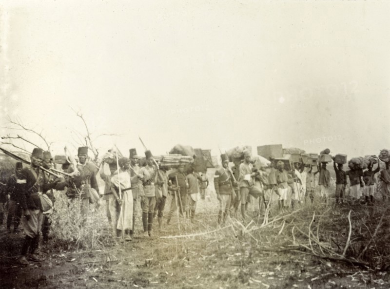 Frederick Stanbury's porters. Frederick Stanbury's porters and servants wait in line holding various items of luggage on a hunting safari to Lake Baringo. British East Africa (Kenya), 1906. Kenya, Eastern Africa, Africa.