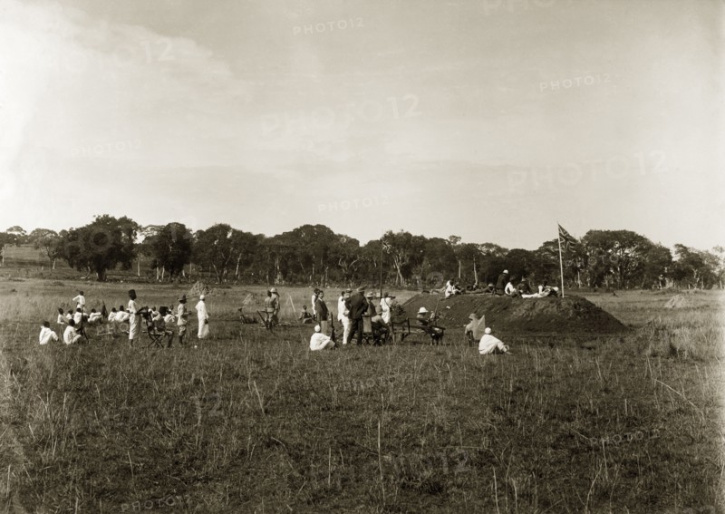 Firing point annual meeting. A group of European men accompanied by their African servants, take practice shots from the top of a mound of earth constructed as a firing point. The original caption suggests this was an 'annual meeting'. Entebbe, Uganda, circa 1930. Entebbe, Central (Uganda), Uganda, Eastern Africa, Africa.