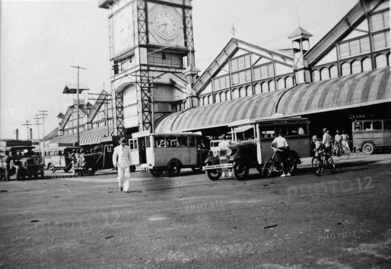 Buses outside the market. Buses parked outside the large clock tower in the central market place. Janjanbureh, Gambia, circa 1935. Janjanbureh, Central River, Gambia, Western Africa, Africa.