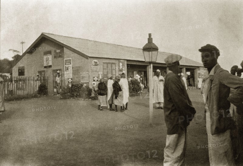 Jos railway station. African men and women mill around on the street outside Jos railway station. Jos, Nigeria, circa 1932. Jos, Plateau (Nigeria), Nigeria, Western Africa, Africa.