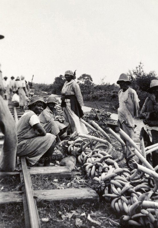 Banana sellers, Uganda. Banana sellers hope to attract passing trade beside a railway track and river. Uganda, circa 1935. Uganda, Eastern Africa, Africa.