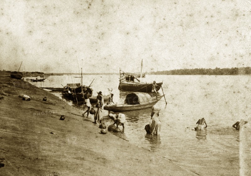 Washing in the River Ganges. People wash themselves in the River Ganges beside several small fishing boats moored off a sandbank. Chandernagore, India, 1890. Chandernagore, West Bengal, India, Southern Asia, Asia.