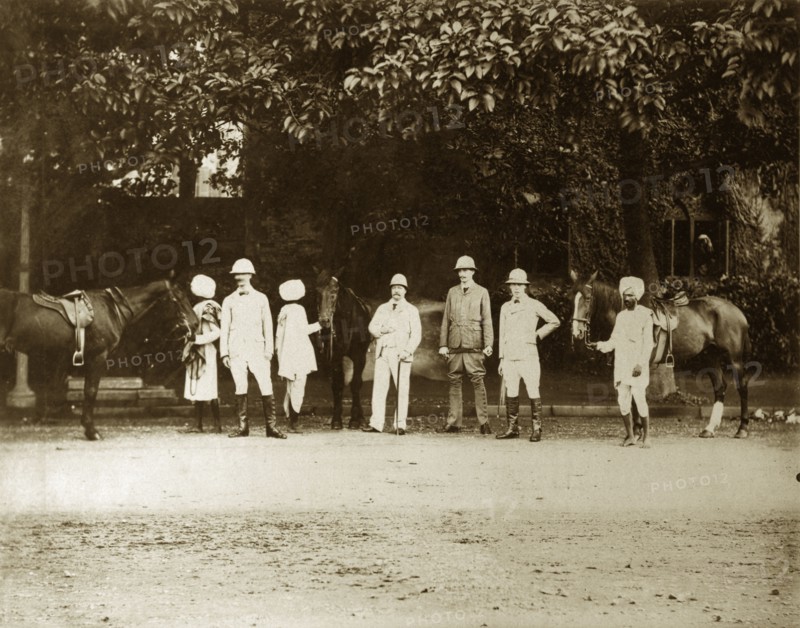 British men with Indian servants. Four British men pose for the camera, their Indian servants waiting with saddled horses behind them. Calcutta (Kolkata), India, August 1895. Kolkata, West Bengal, India, Southern Asia, Asia.