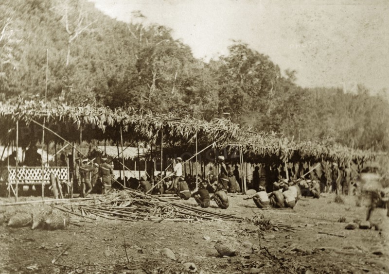 Chin tribesmen, Burma (Myanmar). A group of Chin tribesmen from the Chin Hills crouch beneath a makeshift, grass-roofed shelter. Rakhine, Burma (Myanmar), January 1897., Rakhine, Burma (Myanmar), South East Asia, Asia.