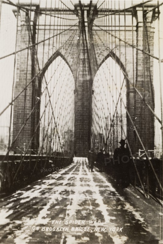 "The Spider Web on Brooklyn Bridge". View along the pedestrian path of Brooklyn Bridge. A printed caption terms this walkway "The Spider Web" in reference to the criss-cross steel-wire used in the bridge's construction. New York, United States of America, circa 1942. New York, New York, United States of America, North America, North America .