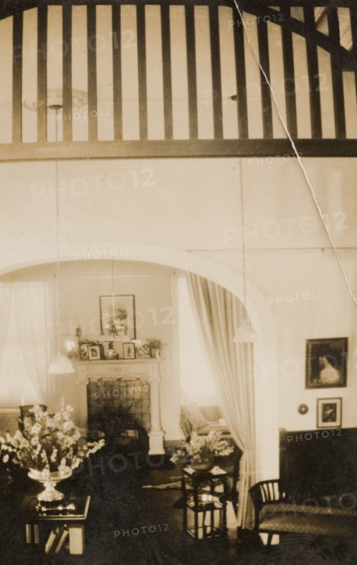 Drawing room of a colonial house, Peru. Interior shot of the drawing room in a house belonging to Archie Cooper, Chief Executive Officer of the Peruvian Corporation, located in the Miraflores district of Lima. The room features tall ceilings and an ornate fireplace, and is furnished with potted flowers and framed pictures. Lima, Peru, 1920. Lima, Lima Metropolitana, Peru, South America, South America .