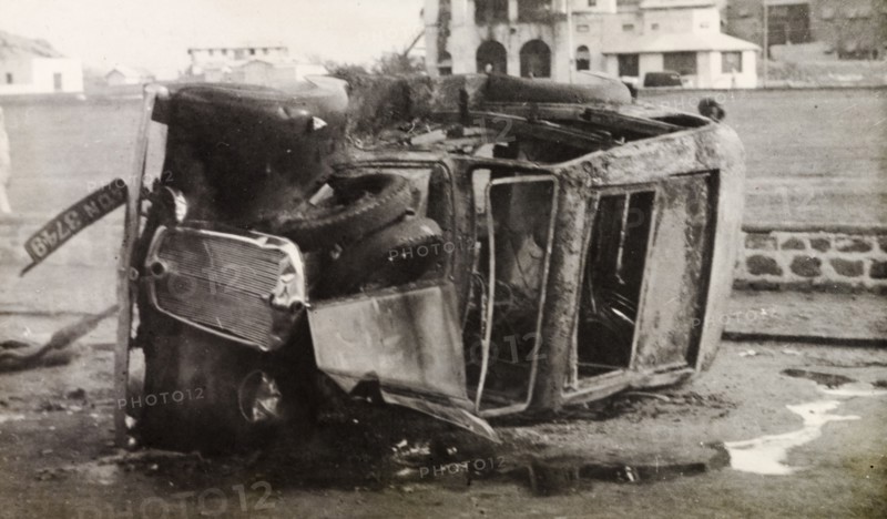 Car destroyed by Arab riots in Aden, 1947. A burnt-out car lies on its side in a street in Aden, during the Arab riots that took place between 1-3 December 1947 in response to the United Nations Partition Plan for Palestine. Aden, Yemen, December 1947. Aden, Adan, Yemen, Middle East, Asia.