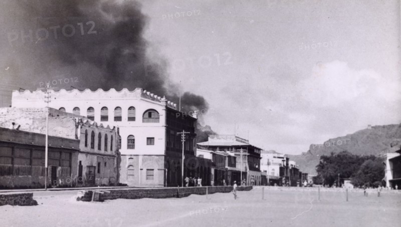 Riot damage in Aden, 1947. A plume of black smoke rises from a building in the Jewish quarter of Aden, during the Arab riots that took place between 1-3 December 1947 in response to the United Nations Partition Plan for Palestine. Aden, Yemen, December 1947. Aden, Adan, Yemen, Middle East, Asia.