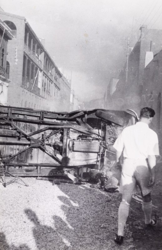 Aftermath of Arab riots in Aden, 1947. A European man walks around an upturned truck lying in the middle of a road in the Jewish quarter of Aden, after the Arab riots that took place between 1-3 December 1947 in response to the United Nations Partition Plan for Palestine. Aden, Yemen, December 1947. Aden, Adan, Yemen, Middle East, Asia.