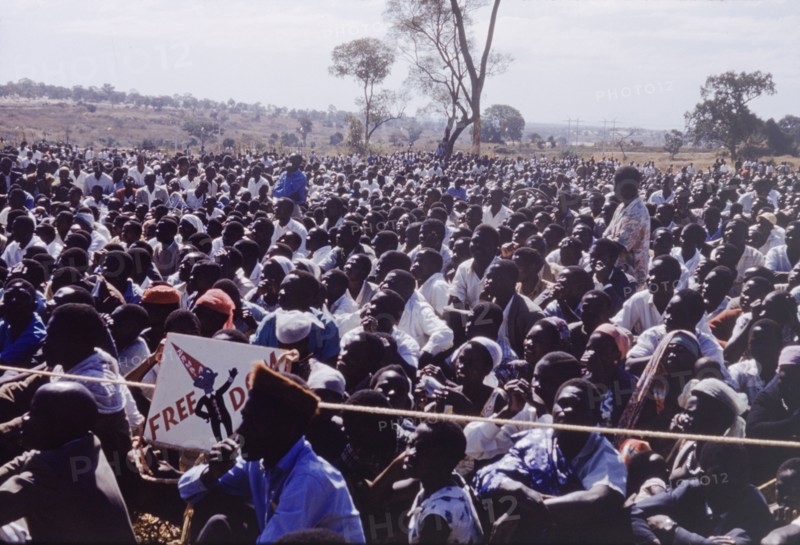 Crowd at United National Independence Party rally. A crowd of Zambian supporters sit and watch a rally by the United National Independence Party. Kitwe, Northerm Rhodesia (Zambia), circa 1962. Nkana-Kitwe, Copperbelt, Zambia, Southern Africa, Africa.