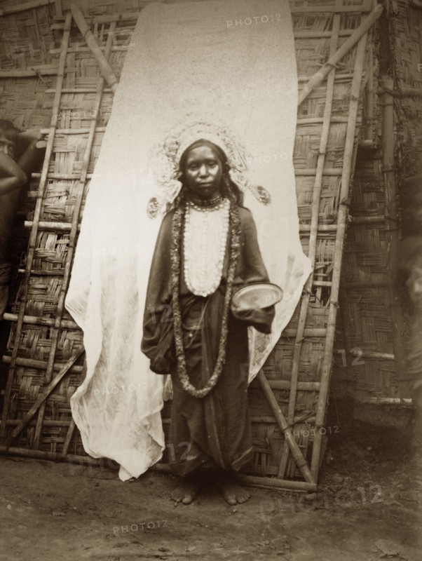 Young mendicant girl. A young female mendicant stands, bowl in hand, dressed in a headdress, a garland strung around her neck. Probably north India, circa 1890. India, Southern Asia, Asia.