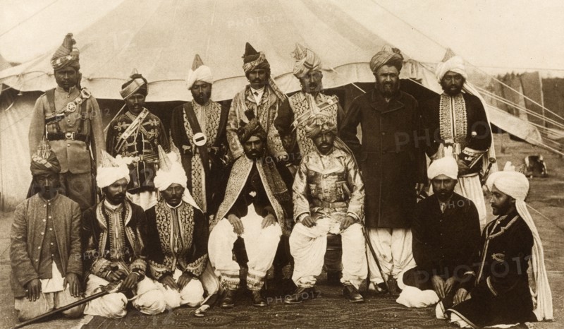 Baluchstan chiefs at the Coronation Durbar. Outdoors group portrait of Mir Mahmud Khan, Khan of Kalat (seated on chair, left) and Mir Kamal Khan, Jam of Las Bela (seated on chair, right), with other chiefs from Baluchistan, at the Coronation Durbar. Delhi, India, January 1903. Delhi, Delhi, India, Southern Asia, Asia.
