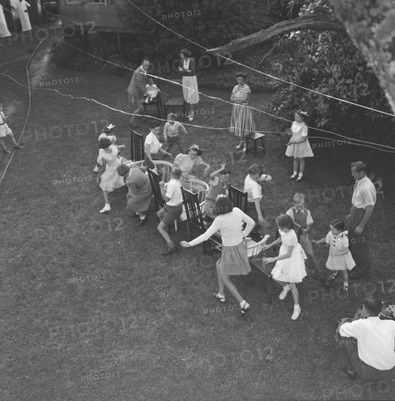 Musical chairs. Overhead view of children at the Button's party playing musical chairs in a garden. Kenya, 14 December 1952. Kenya, Eastern Africa, Africa.
