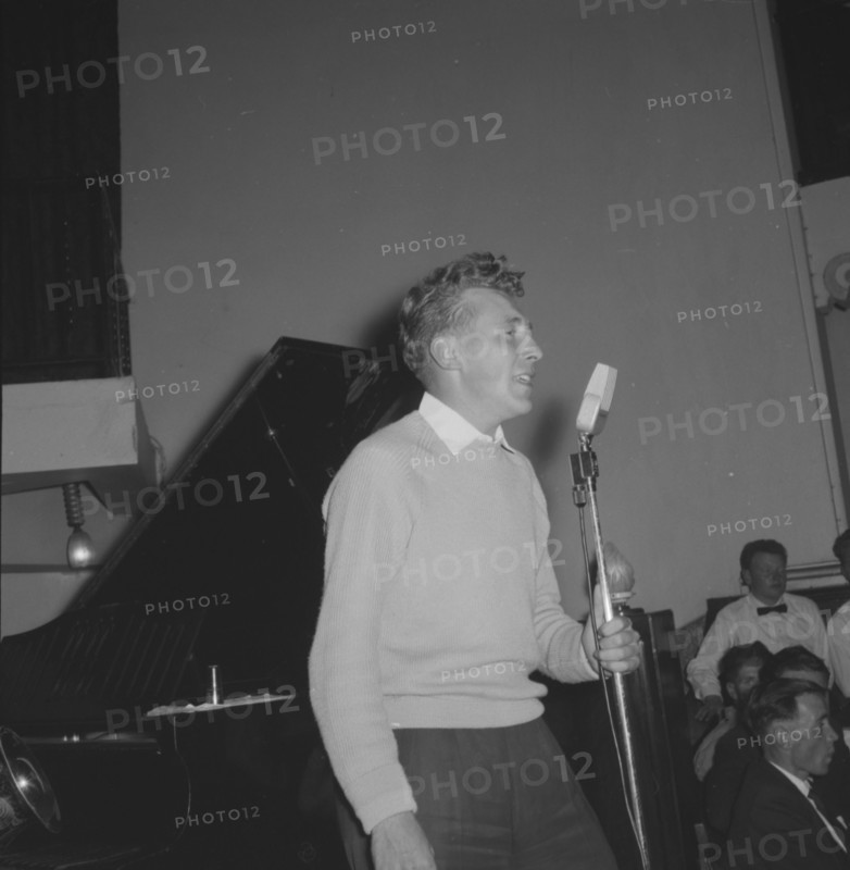 Jazz Ball singer. A casually dressed singer, supported by a band, clutches an upright microphone as he performs at a Jazz Ball. Kenya, 21 September 1957. Kenya, Eastern Africa, Africa.