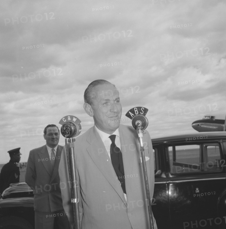 Lennox-Boyd's broadcast. Alan Tindal Lennox-Boyd (1904-1983) broadcasts a speech over microphones marked 'C & W' and 'ABS' on his arrival to a Kenyan airstrip. Kenya, 11 October 1957. Kenya, Eastern Africa, Africa.