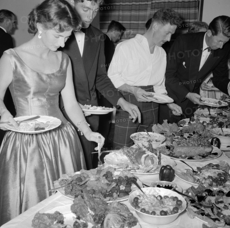 Buffet supper. Formally dressed guests at the Orme-Smith 21st birthday party queue up to help themselves to a luxurious buffet supper. Kenya, 9 November 1957. Kenya, Eastern Africa, Africa.