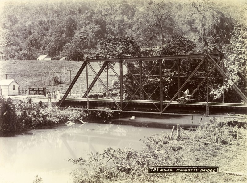 Railway track over Maggotty Bridge. A man operating a hand cart travels across a metal railway bridge, identified as 'Magotty Bridge', spanning a small river. Jamaica, circa 1895. Jamaica, Caribbean, North America .