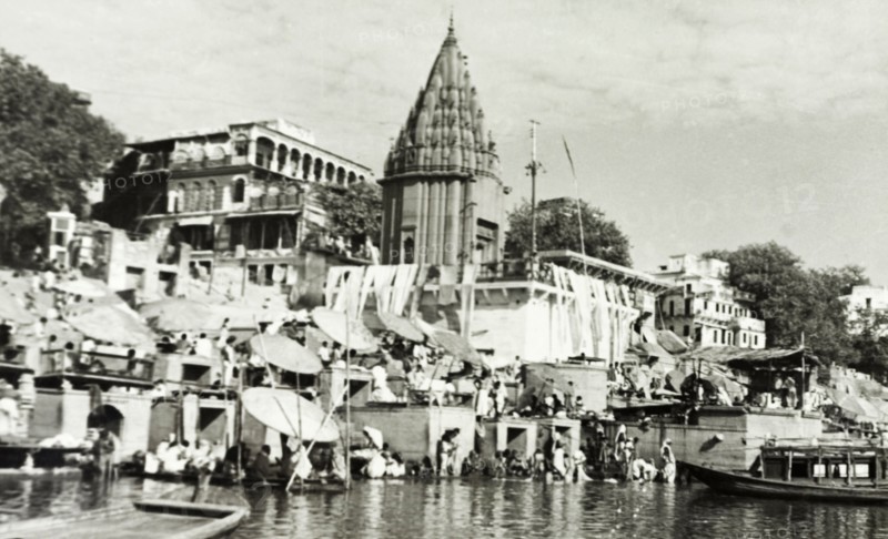 Hindu temple at Benares. Religious pilgrims sit beneath large umbrellas at a ghat (stepped wharf) on the River Ganges at Benares, one of Hinduism's holiest sites. The famous Hindu temples of Scindia Ghat and Manikarnika Ghat are located nearby. Benares, United Provinces (Varanasi, Uttar Pradesh), India, circa 1925. Varanasi, Uttar Pradesh, India, Southern Asia, Asia.