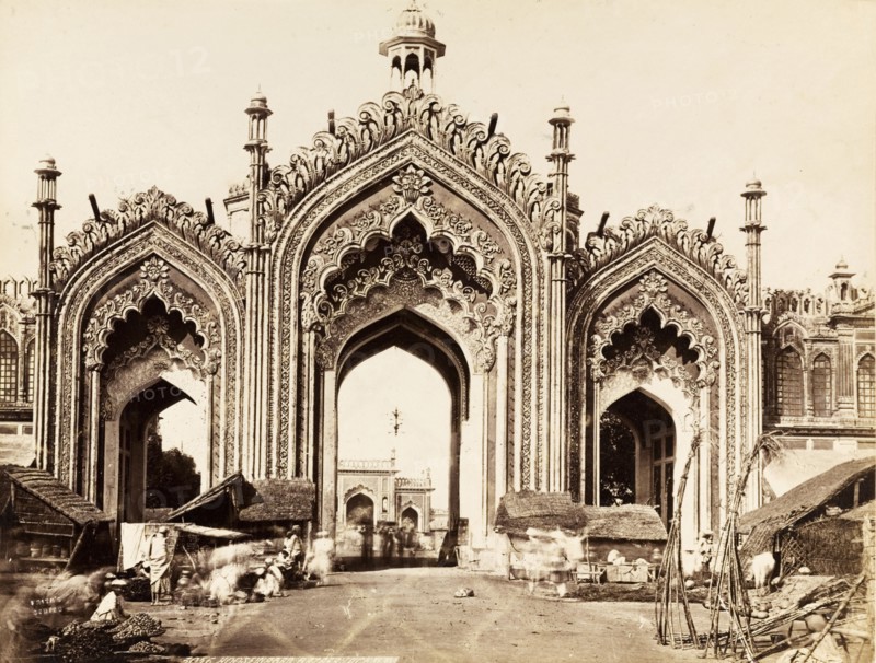 Gateway to the Hussainabad Imambara. The decorative arches of the gateway leading to the Hussainabad Imambara. Makeshift shops and stalls line the road in front of the gate. Lucknow, North Western Provinces (Uttar Pradesh), India, circa 1875. Lucknow, Uttar Pradesh, India, Southern Asia, Asia.