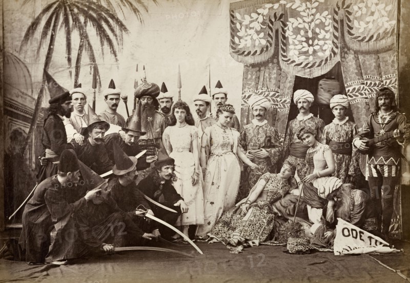 Cast of Lalla Rookh. The European cast in a pantomime of Lalla Rookh. The group stand on stage in front of a painted backcloth, dressed in a variety of Oriental and medieval costumes with accessories including turbans, sorcerer's pointed hats and exaggerated beards. Calcutta (Kolkata), India, circa 1885. Kolkata, West Bengal, India, Southern Asia, Asia.