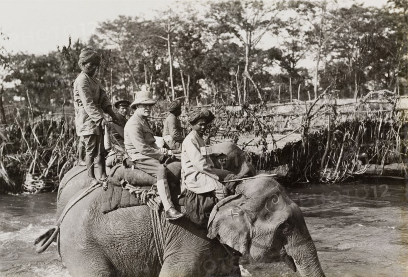 Sir Lockwood Smith-Dorien on a hunt. British Army General, Sir Horace Lockwood Smith-Dorien, rides an elephant across a river during a royal hunt in Chitwan Valley. The Maharajah of Nepal hosted the hunt for King George V shortly after the Coronation Durbar in Delhi. Narayani, Nepal, circa 18 December 1911., Narayani, Nepal, Southern Asia, Asia.