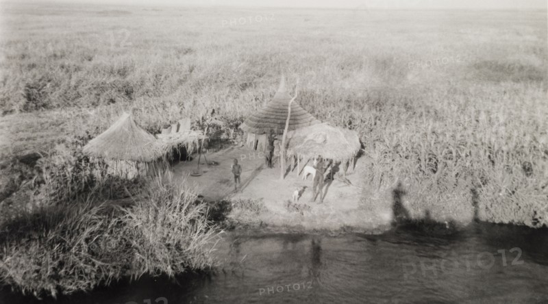 Settlement in the sudd. A tiny settlement consisting of round, thatched huts, located on a riverbank in the sudd, a vast area of swampland formed by the River Nile in southern Sudan. The photographer comments of the area: "If the Nubian desert is accounted one of the world's most barren and inhospitable regions, the sudd must be the dreariest and most featureless". Malakal, Sudan, 1946. Malakal, Upper Nile, Sudan, Eastern Africa, Africa.