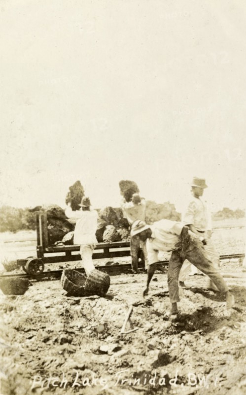 Extracting asphalt from the Pitch Lake. Labourers load lumps of asphalt extracted from Trinidad's Pitch Lake onto a waiting rail car. La Brea, Trinidad, circa 1910. La Brea, Trinidad and Tobago, Trinidad and Tobago, Caribbean, North America .