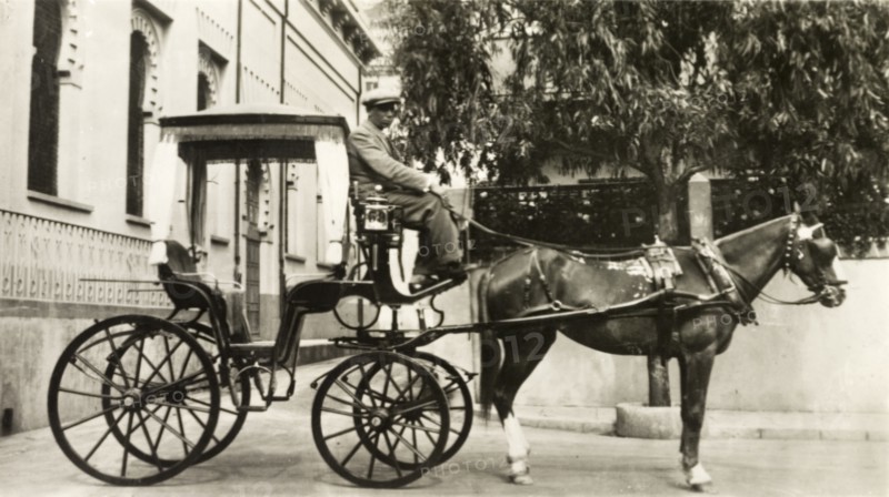 Hackney carriage, Gibraltar. A horse-drawn hackney carriage waits outside a building in a city street. Gibraltar, circa 1920. Gibraltar, Gibraltar, Gibraltar, Mediterranean, Europe .