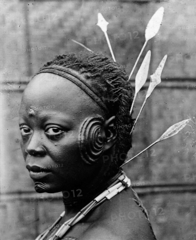 Oyster' cicatrisation. Portrait of a Congolese woman, her face scarred with a prominent 'oyster' cicatrisation. Congo Free State (Democratic Republic of Congo), circa 1905. Congo, Democratic Republic of, Central Africa, Africa.