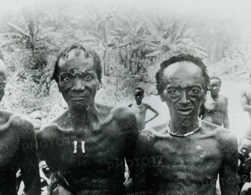 Old men of Mangi. Portrait of two elderly Congolese men, survivors of mercenary raids led by King Leopold II's soldiers. Both men display traditional scarification marks on their faces and chests. Congo Free State (Democratic Republic of Congo), circa 1905. Congo, Democratic Republic of, Central Africa, Africa.