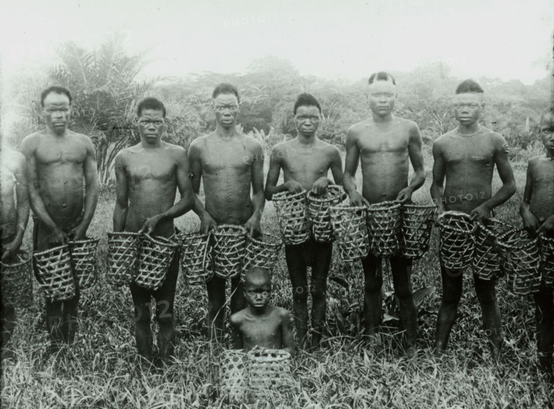 Congolese rubber slaves. A group of male slaves pose, holding empty baskets, as they prepare to journey into the forest to collect rubber vines for the Anglo-Belgian India Rubber company (ABIR). Congo Free State (Democratic Republic of Congo), circa 1905. Congo, Democratic Republic of, Central Africa, Africa.