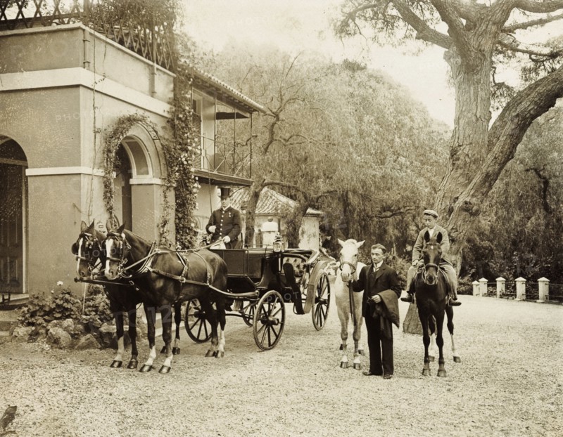 Horses at the ready. Servants wait with horses at the ready in the driveway to a large colonial house. One of several photographs taken during a royal visit to Gibraltar by King Edward VII (1841-1910) and Kaiser Wilhelm II (1859-1941), this residence may have accommodated the monarchs during their stay. Gibraltar, 1904., Gibraltar, Gibraltar, Mediterranean, Europe .