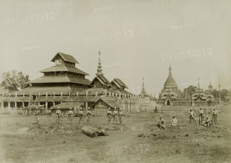 Wuntho Palace and the 'Pon-gyi kyaung'. British Army soldiers pose in front of Wuntho Palace (left) and the town's 'Pon-gyi kyaung' (Buddhist monastery). The group are pictured shortly after British forces captured Wuntho following a conflict with Burmese rebels. Wuntho, Burma (Myanmar), 1891. Wuntho, Sagaing, Burma (Myanmar), South East Asia, Asia.